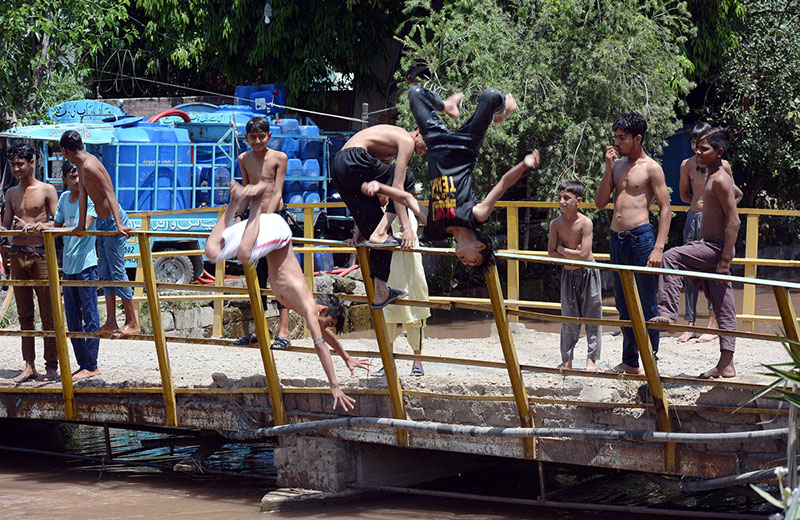 Youngsters jumping and bathing in the canal to get relief from the hot weather in the city