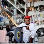 Blacksmith sharpening the knives at his workplace to be used for slaughtering sacrificial animals during Eidul Azha