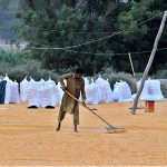 A laborer busy in spreading corn seeds for drying purpose in his field