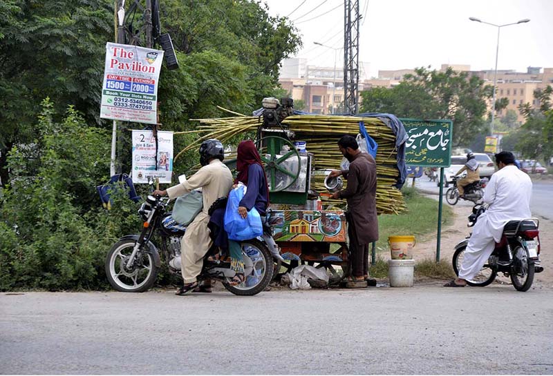 A vendor is selling sugarcane juice at his roadside setup