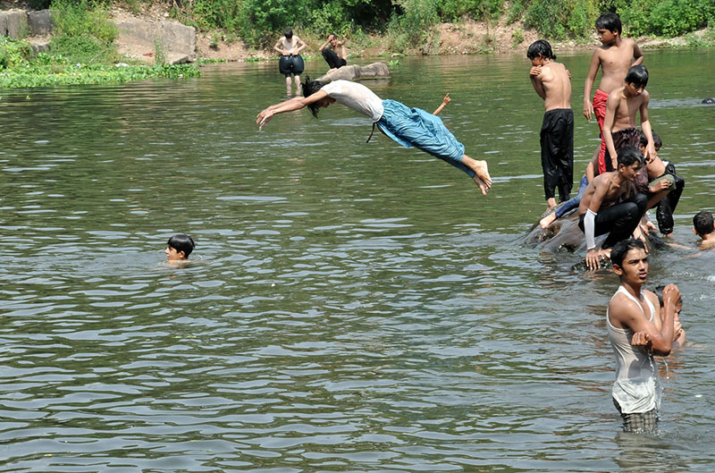 Youngster enjoys jumping and bathing in rawal lake to beat the heat at Federal Capital