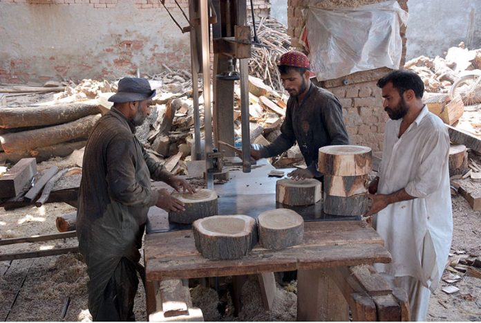 Carpenter busy in preparing wooden bases to be used by butchers to cut meat in pieces on sacrifice day of Eid ul-Azha