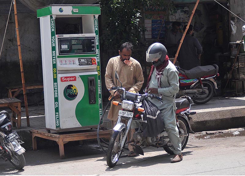A motorcyclist taking fuel from an illegal petrol pump at the roadside