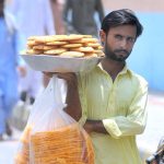 A street vendor selling edible items while shuttling on Masoom Shah Road