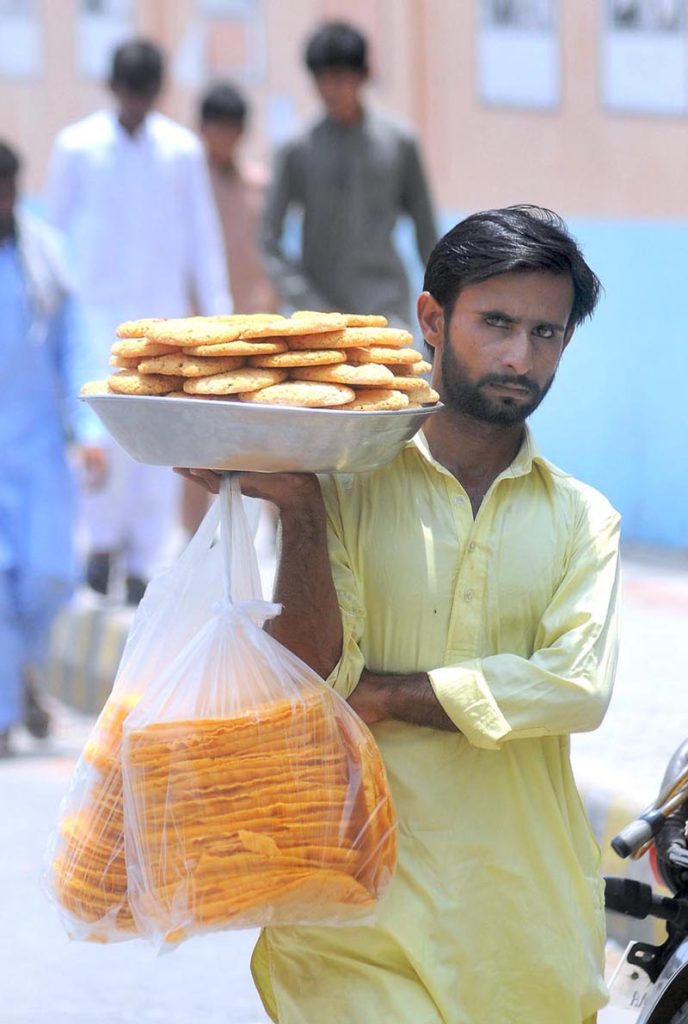 A street vendor selling edible items while shuttling on Masoom Shah Road