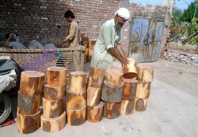 vendor selling wooden bases to be used by butchers to cut meat in pieces on sacrifice day of Eid ul-Azha