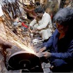 A blacksmiths sharpen the knives and axes at Shahi Bazar to be used for slaughtering sacrificial animals in connection with upcoming Eid ul Azha