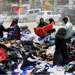 People selecting and purchasing old cloth from roadside vendors