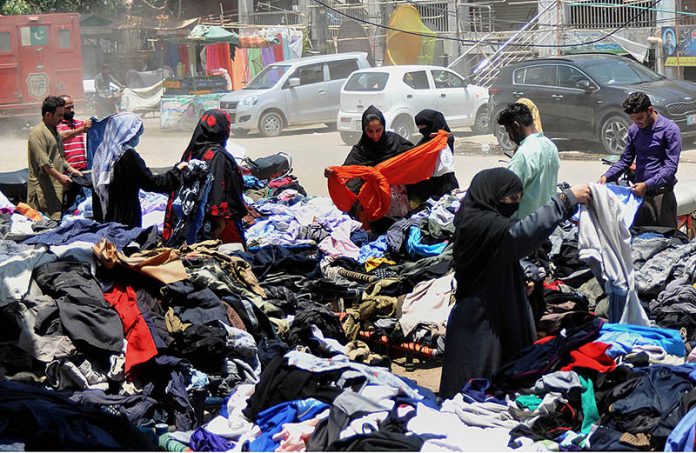 People selecting and purchasing old cloth from roadside vendors