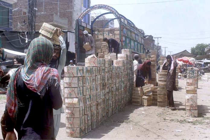 Laborers off loading fruit crates from delivery truck at the fruit market