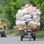 A person riding an overloaded tricycle rickshaw which may cause any mishap