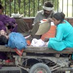 Family is resting under shade during hot weather in the city