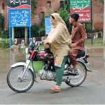 Woman riding a motorcycle along with a boy at College Road