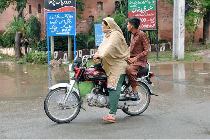 Woman riding a motorcycle along with a boy at College Road