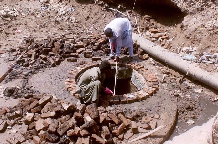 Labourers busy in construction work of sewerage manhole at water works road