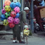A disable street vendor selling colorful balloons to earn bread and butter for his family