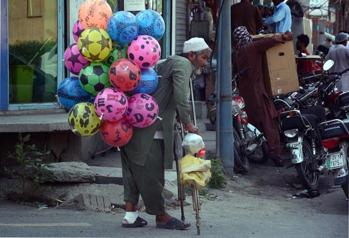 A disable street vendor selling colorful balloons to earn bread and butter for his family