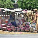 A woman vendor displaying and selling household handmade items at her roadside setup