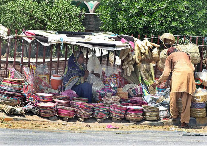 A woman vendor displaying and selling household handmade items at her roadside setup