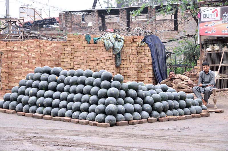 A vendor waiting for customers to sell watermelon at his roadside setup