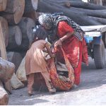 A woman and her child collect firewood from timber market for domestic use