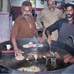 Vendors making traditional food item Chapli kabab at his workplace for costumers near Ghouri town at Federal Capital