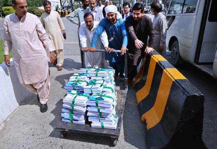 Staffers pushing cart loaded with copies of Pakistan Economy Survey 2022-23 at Parliament House