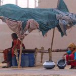 A gypsy girl washing pots infront of a makeshift home