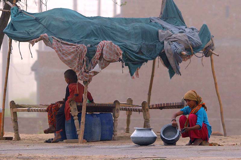 A gypsy girl washing pots infront of a makeshift home