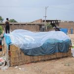 Gypsy people covering their makeshift home with polythene sheets to protect them from the rain near Vehari Chowk