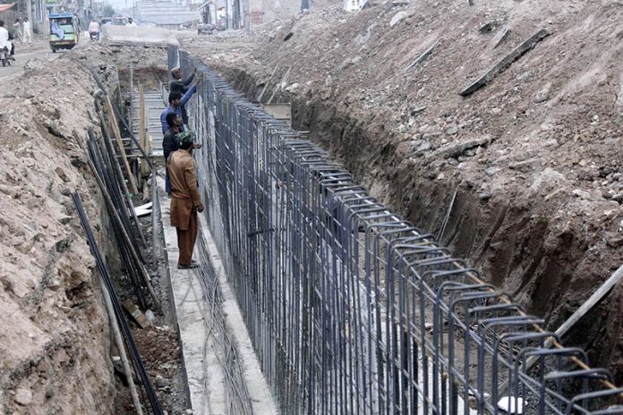 Laborers are engaged in the construction work of a flyover at Muzaffarabad Road