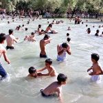 Youngsters taking bath in water pond to get relief from the hot weather in city