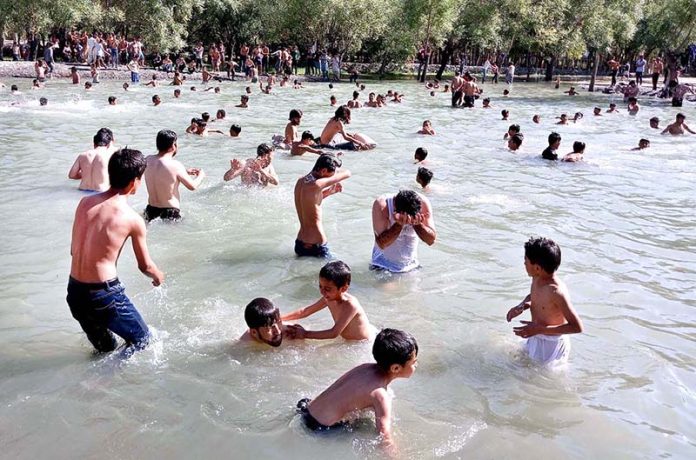 Youngsters taking bath in water pond to get relief from the hot weather in city