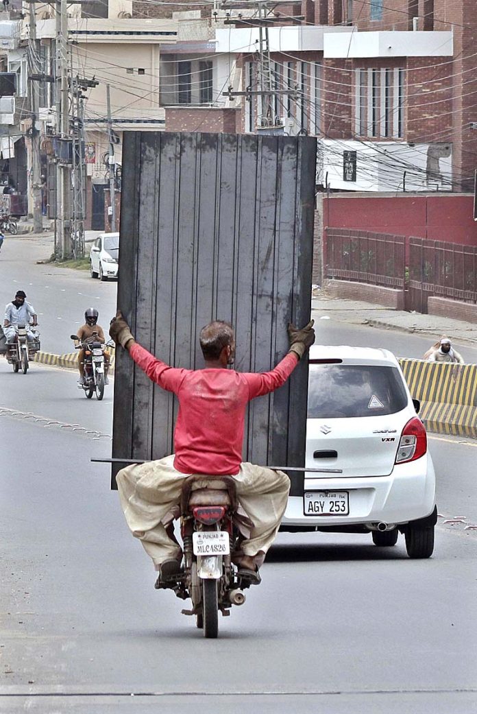 A person holding iron door while sitting on rear seat of motorcycle