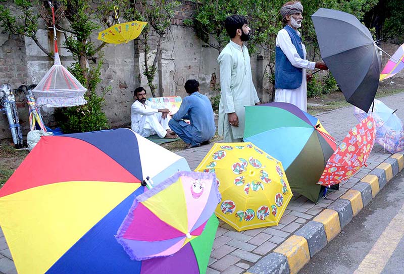 An aged man is displaying and selling umbrella at roadside in the city