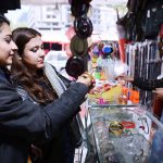 Female visitors selecting and purchasing artificial jewelry from a roadside vendor during their visit