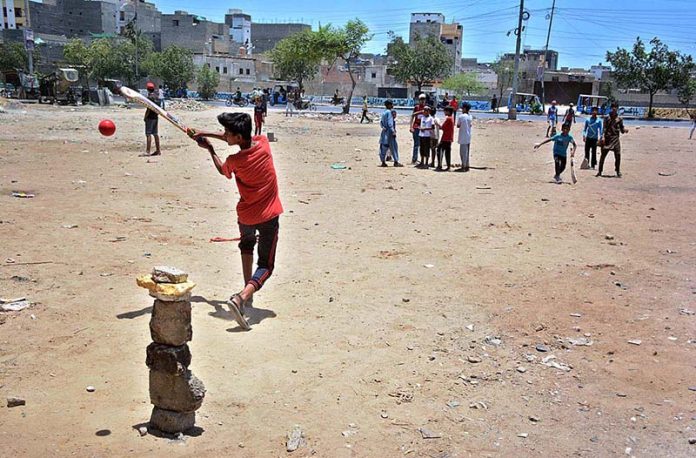 Children playing cricket in a local ground at Korangi area