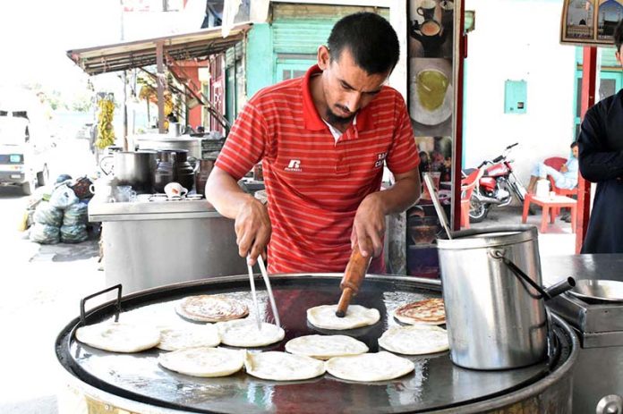 A vendor busy in preparing traditional parathas at his road side setup to attract customers