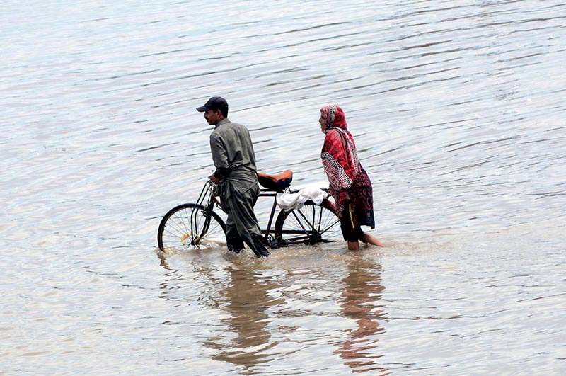 Motorcyclist passing through rain water accumulated on the road during rain in the city
