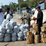 People purchasing coal for BBQ from roadside vendor at Charsadda Road on the occasion of Eid al-Adha