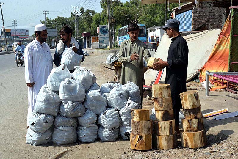 People purchasing coal for BBQ from roadside vendor at Charsadda Road on the occasion of Eid al-Adha