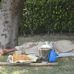 A street vendor resting on the rodside after selling edible items