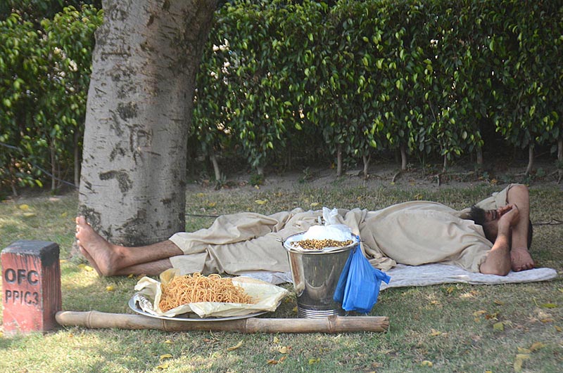 A street vendor resting on the rodside after selling edible items