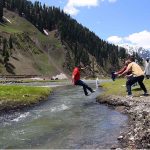 Youngster jumping over a stream at Babusar Top road