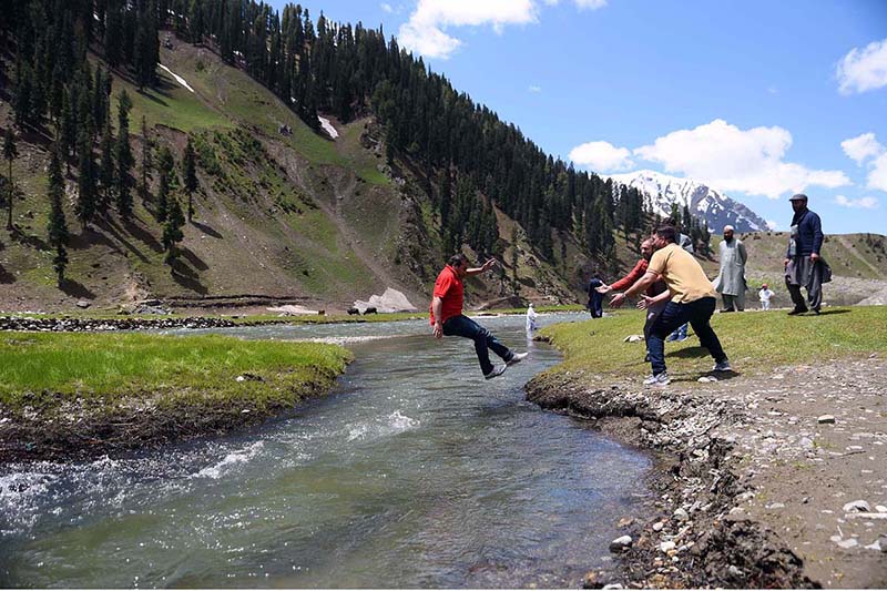 Youngster jumping over a stream at Babusar Top road