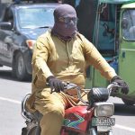 A motorcyclist covered himself with a handkerchief to avoid the heat stoke during a hot day in the city