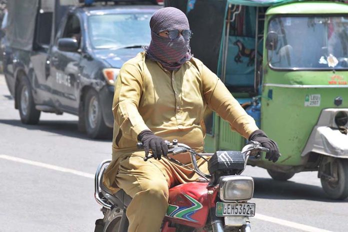 A motorcyclist covered himself with a handkerchief to avoid the heat stoke during a hot day in the city
