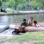 A view of sewerage water dropping in the Canal making water polluted, creating environmental problems while gypsy children playing on the sewerage water pipe