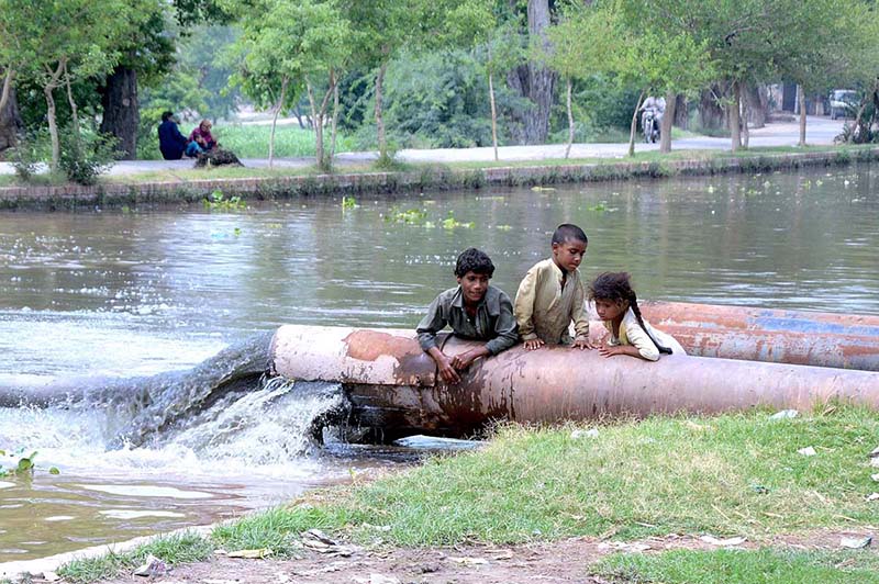 A view of sewerage water dropping in the Canal making water polluted, creating environmental problems while gypsy children playing on the sewerage water pipe