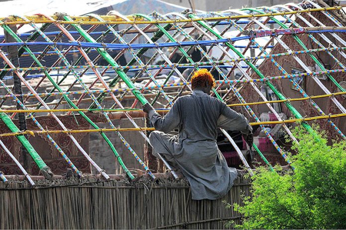A gypsy person assembling a makeshift home on a roadside